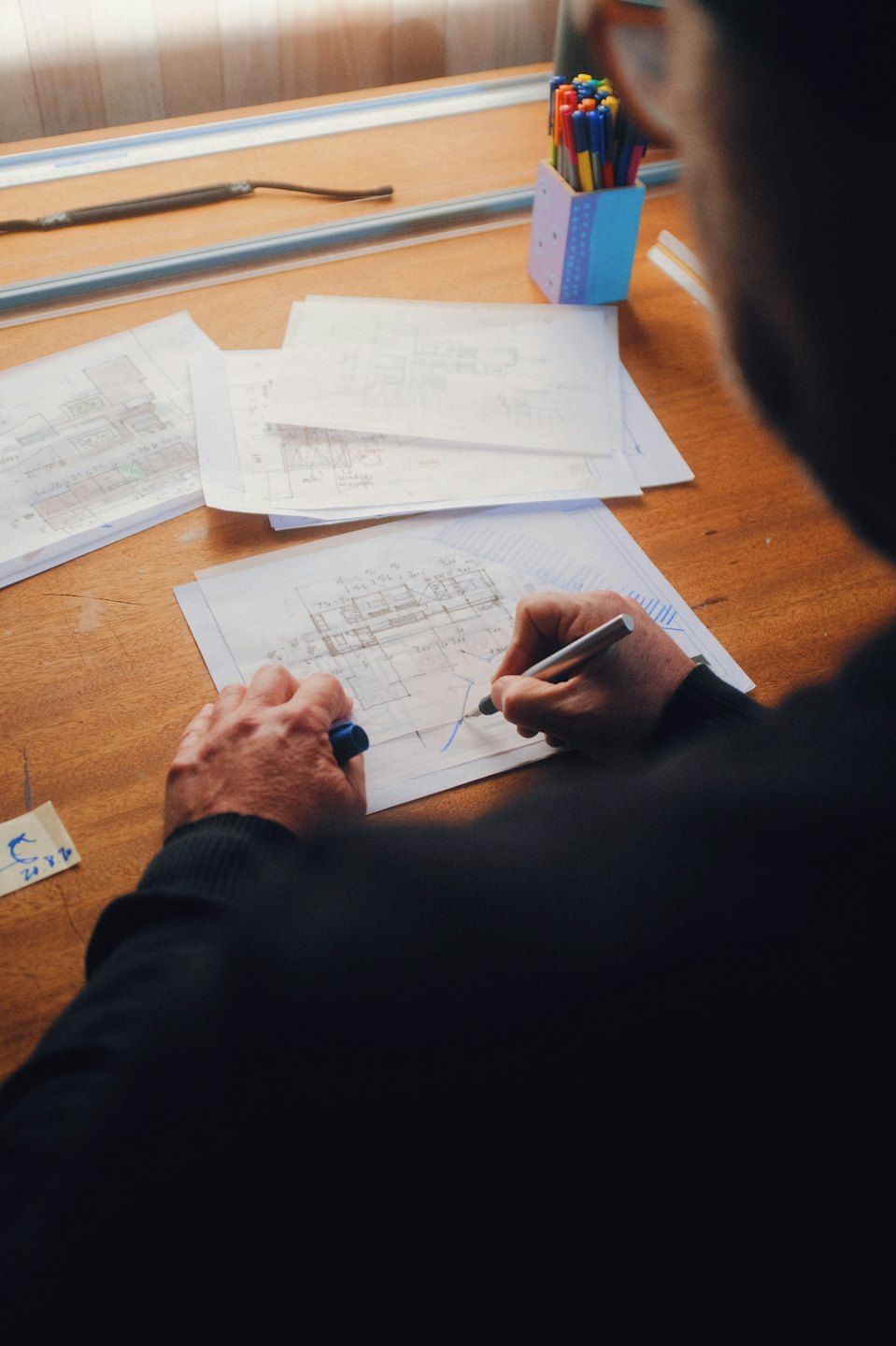 Person drawing architectural plans on a drafting table.