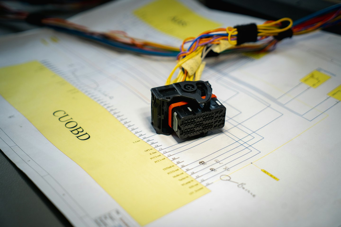 Electrical connector with colorful wires on engineering blueprints.